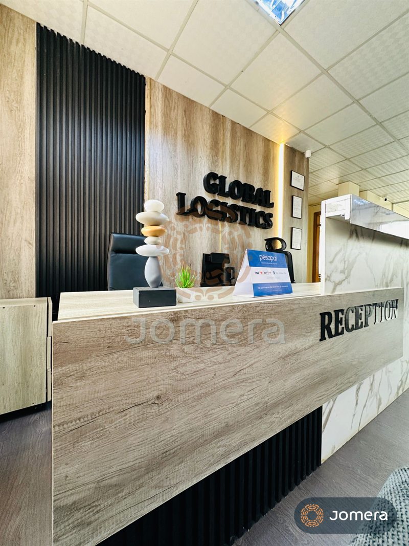 Office reception with a timber-look and marble desk, black fluted wall panels, raised signage letters and a stacked-stone sculpture